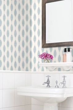 a white sink sitting under a bathroom mirror next to a wall mounted faucet