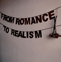 there is a sign on the wall that says from romance to realism, and two strings attached to it