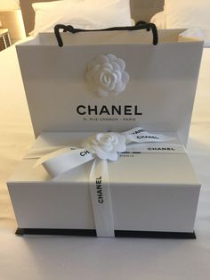 a chanel gift bag sitting on top of a bed