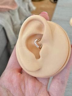 a close up of a person's hand holding a fake ear with a ring on it