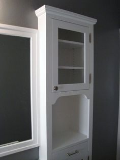 a white cabinet sitting in the corner of a bathroom