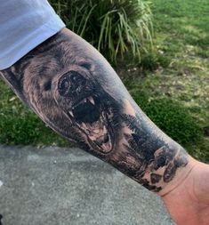 a man's arm with a black and grey bear tattoo on the left forearm