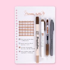 a notebook with some pens and other items in it on top of a pink background