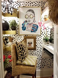 a living room with polka dot wallpaper and a painting on the wall next to a wicker chair