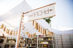 a white tent with an arrow sign hanging from it's side next to bookshelves