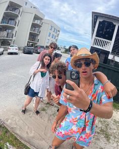 a group of people standing on the side of a road taking a selfie with a cell phone