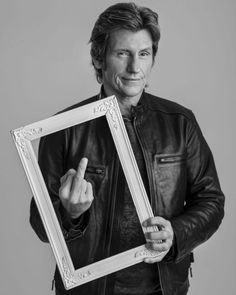 a man in a leather jacket is holding up a framed photo and pointing to the side