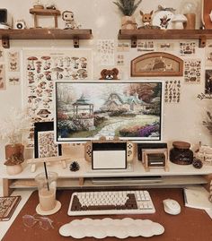 a desk with a computer, mouse and other items on top of it in front of a wall full of pictures