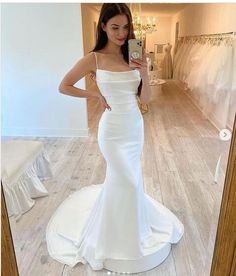 a woman taking a selfie in front of a mirror wearing a white wedding dress