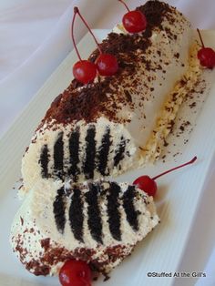 a white plate topped with a piece of cake covered in whipped cream and cherries