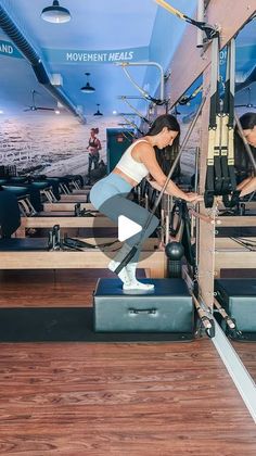 two women working out on exercise equipment in a large room with wooden floors and blue walls