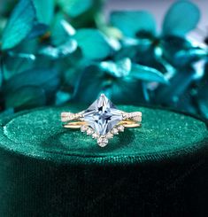 an engagement ring sitting on top of a green velvet box