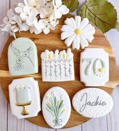 decorated cookies on a wooden platter with flowers and leaves in the background, including one that reads 70