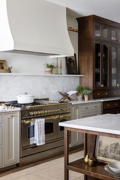 a kitchen with marble counter tops and stainless steel stove top ovens, cabinets, and an island in the middle