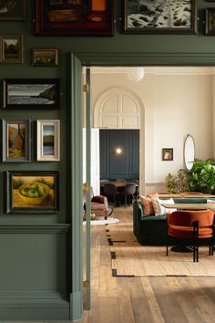 a living room filled with furniture and framed pictures on the wall above an open doorway