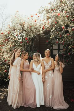 a group of women standing next to each other in front of some bushes and flowers