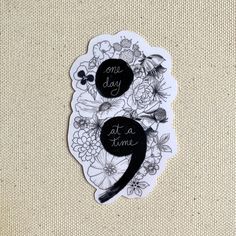 one day at a time sticker in black and white with flowers on the back