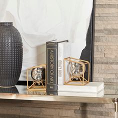 a couple of books sitting on top of a shelf next to a vase and lamp