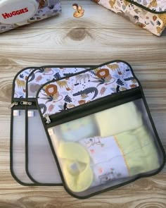 three baby bibs and one diaper bag on a wooden table