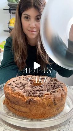 a woman is holding up a cake on a plate