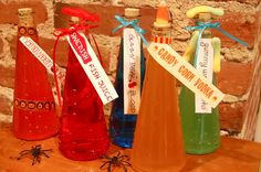 three different colored bottles with labels on them sitting on a table next to a brick wall