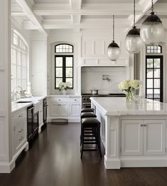 a large kitchen with white cabinets and black accents on the walls, along with dark wood flooring