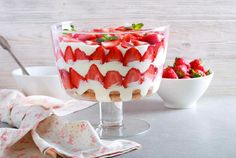 a dessert with strawberries in a glass dish on a table next to other dishes