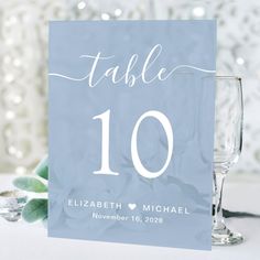 a table number card sitting on top of a table next to two wineglasses