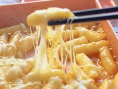 someone is eating some kind of pasta with cheese and sauce on it, while holding chopsticks