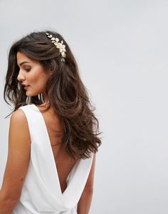 a woman wearing a white dress with a flower headpiece in her hair and looking off to the side