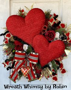 a wreath with two red hearts on it and ribbons hanging from the front door,