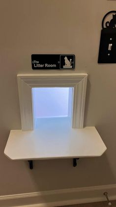 there is a white shelf with a sign on the wall above it that says litter room