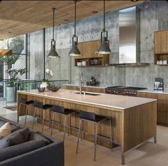 a large kitchen with lots of counter space and hanging lights over the island in front of it