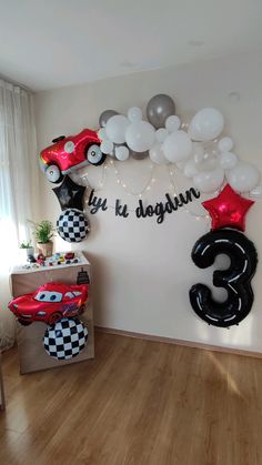 a room filled with balloons and cars on the wall next to a wooden floor in front of a window