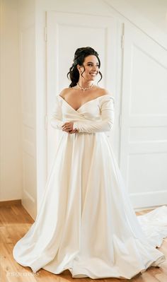 a woman in a white dress standing on a wooden floor with her arms folded out