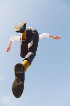 a man flying through the air while riding a skateboard in front of a blue sky