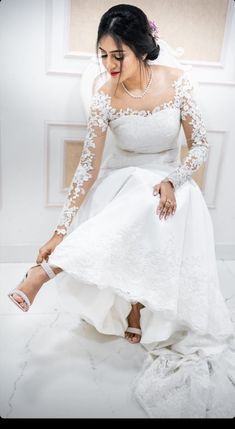 a woman in a white wedding dress sitting on a chair with her legs crossed and wearing high heels