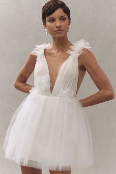 a woman in a short white dress with flowers on the top and bottom, posing