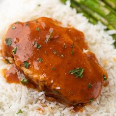 a plate with rice, asparagus and meat covered in gravy on it