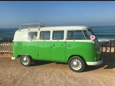 a green and white vw bus parked on the side of a road next to the ocean