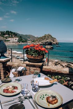 two plates with food are sitting on an outdoor table overlooking the ocean and town in the distance