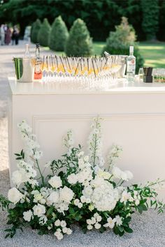 white flowers and greenery are on display at an outdoor bar