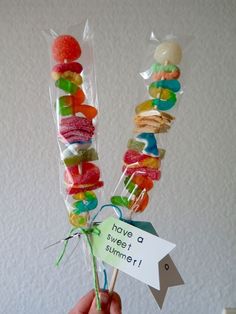 a person holding up some candy sticks with candies on them and a sign that says have a sweet summer