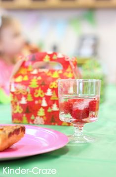 a pink plate topped with pizza next to a glass of water and a box on a table