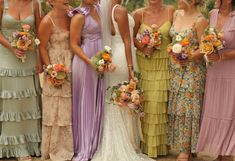 a group of women standing next to each other wearing dresses and holding bouquets in their hands