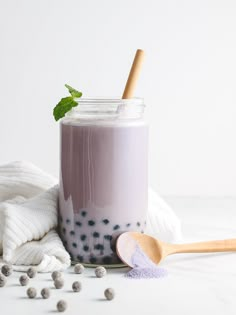 a jar filled with purple liquid next to a wooden spoon and white towel on the table