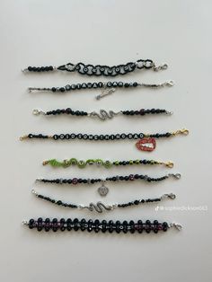 five bracelets with different designs and colors are lined up on a white table top