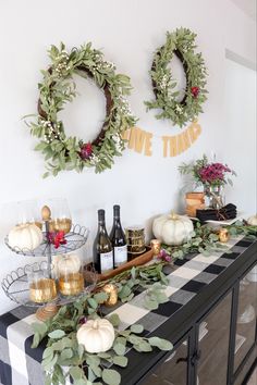 two wreaths are hanging on the wall above a table with wine bottles and glasses