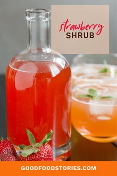 a bottle of strawberry shrub next to a bowl of strawberries and a glass of orange juice