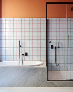 a bathroom with orange walls and white tiles on the wall, along with a bathtub